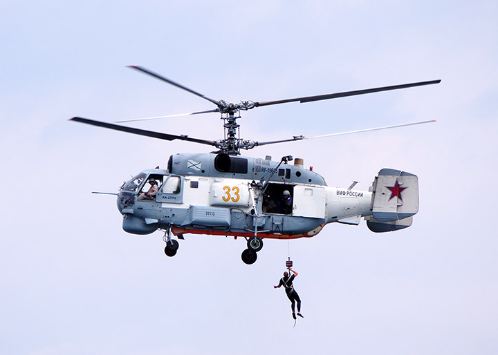 На борт зависшего поисково-спасательного вертолета Ка-27ПС при помощи лебедки поднимают человека